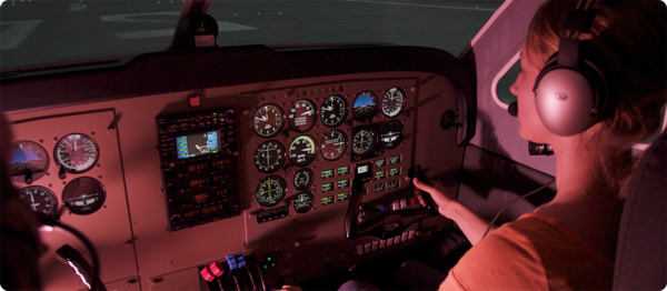 一名女航空学生坐在飞行员座位上，检查飞机的各种仪器.