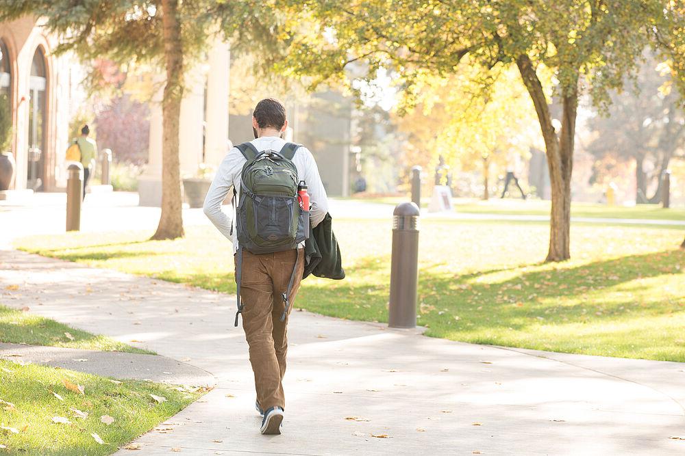 Student walking on a sidewalk wearing a backpack