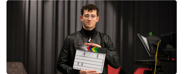 一个学生站在电影拍摄现场，手里拿着拍板.
